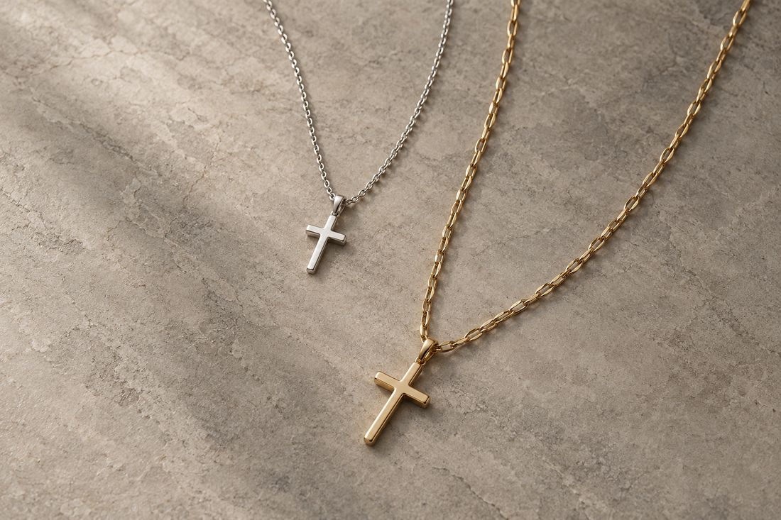 Layered silver and gold cross necklaces on a neutral stone surface