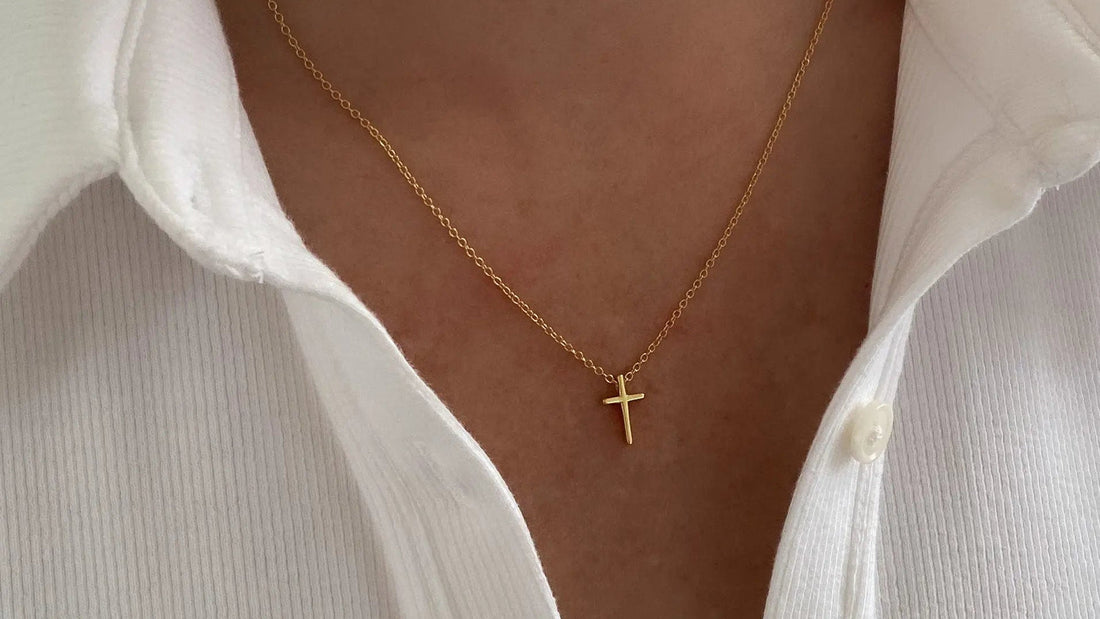 Layered gold and silver cross necklaces styled at different lengths on a neutral neckline