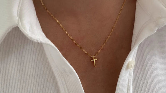 Layered gold and silver cross necklaces styled at different lengths on a neutral neckline