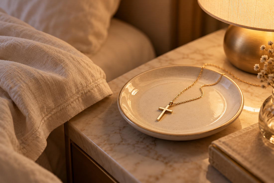 Gold cross necklace resting on a bedside jewelry dish before sleep
